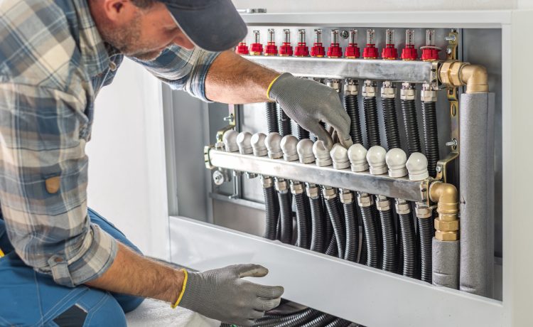 The worker's hands adjusts and checks valves of a underfloor heating distributor. Underfloor heating.